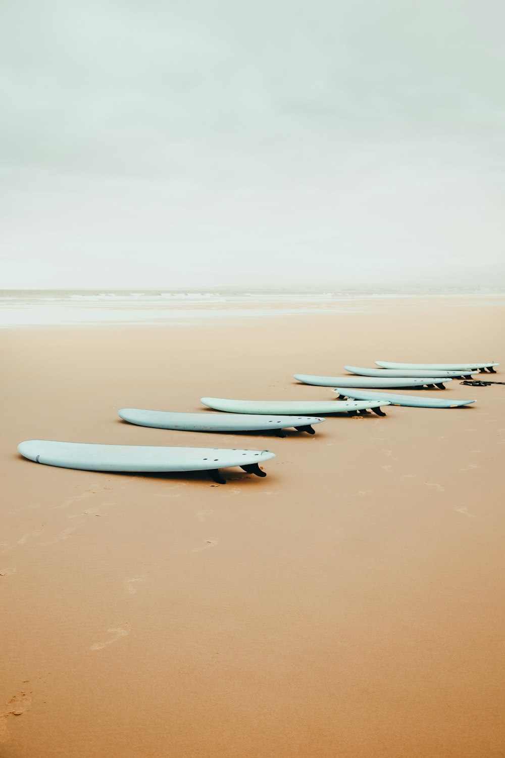 a row of surfboards sitting on top of a sandy beach