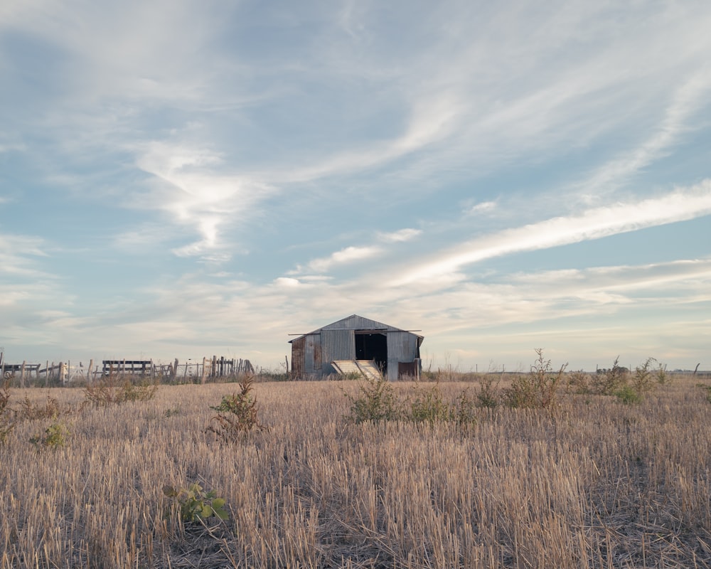 a barn in the middle of a dry grass field