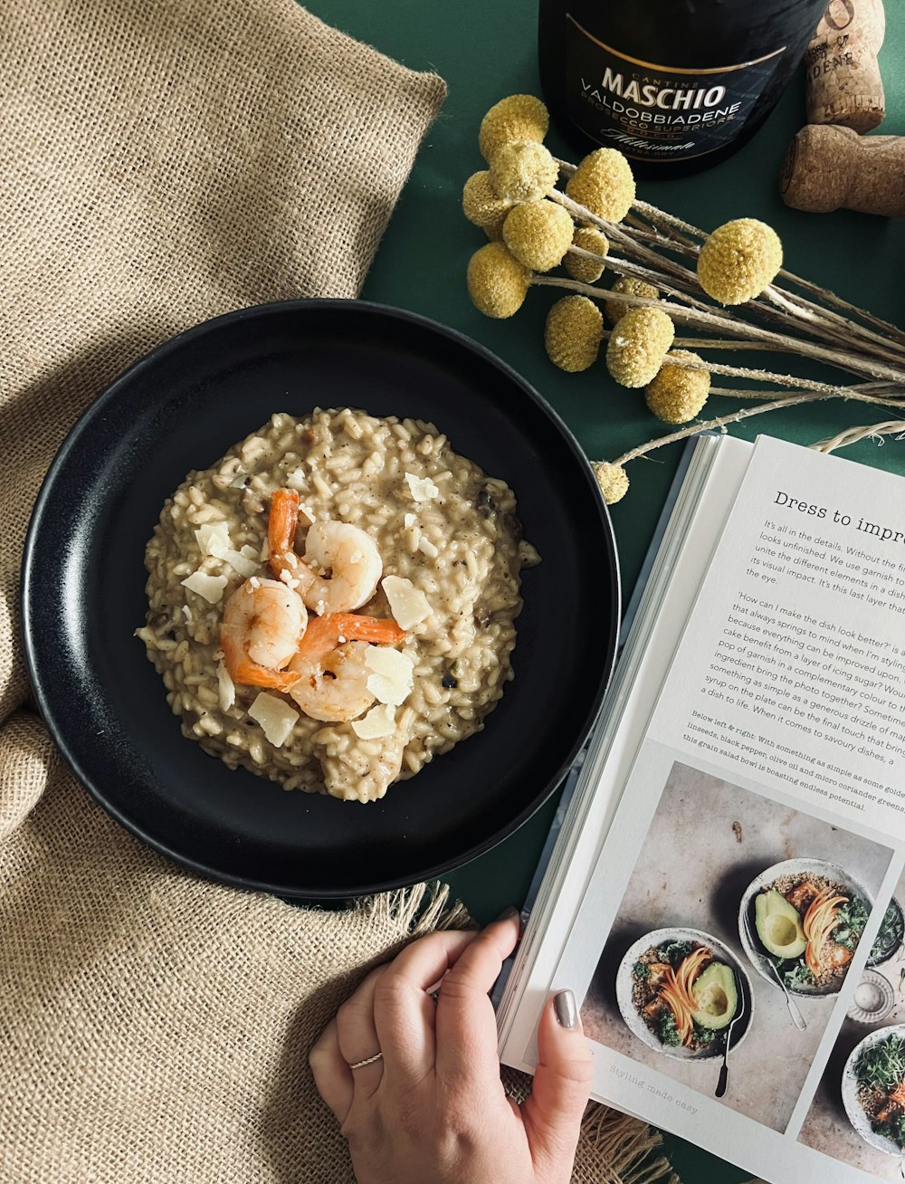 a person reading a book next to a bowl of oatmeal