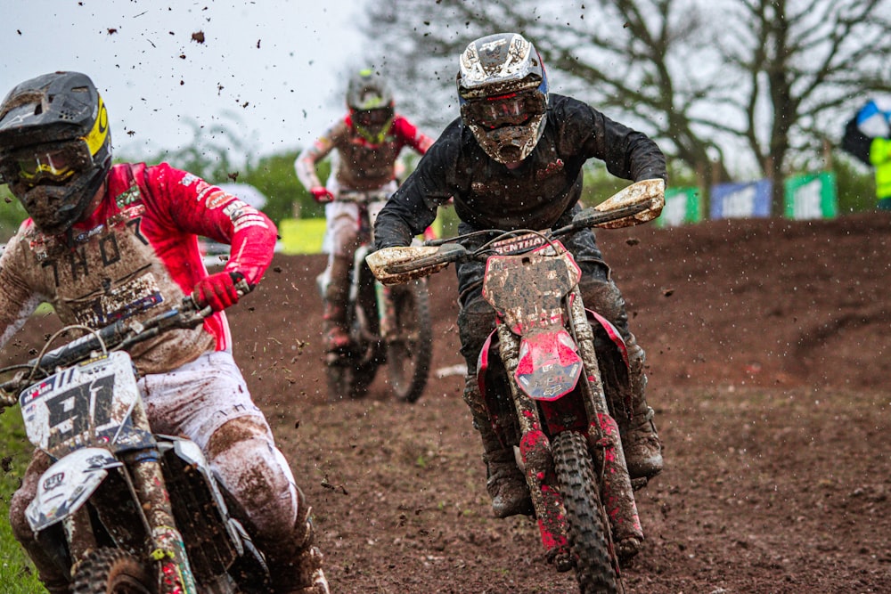 a group of people riding dirt bikes on top of a dirt field