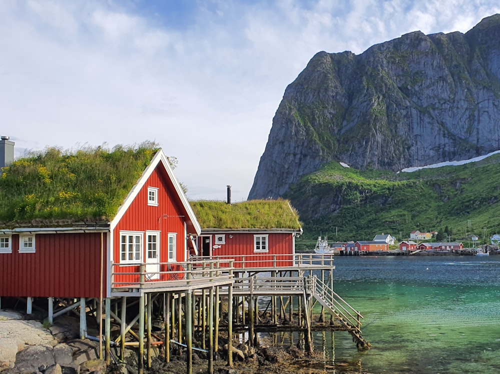 a red house with a green roof next to a body of water