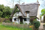 Exterior view of a stylish cottage surrounded by blooming flowers and greenery.