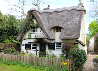 a white house with a thatched roof and a wooden fence