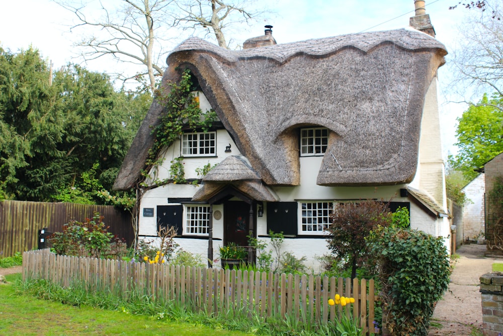 a white house with a thatched roof and a wooden fence