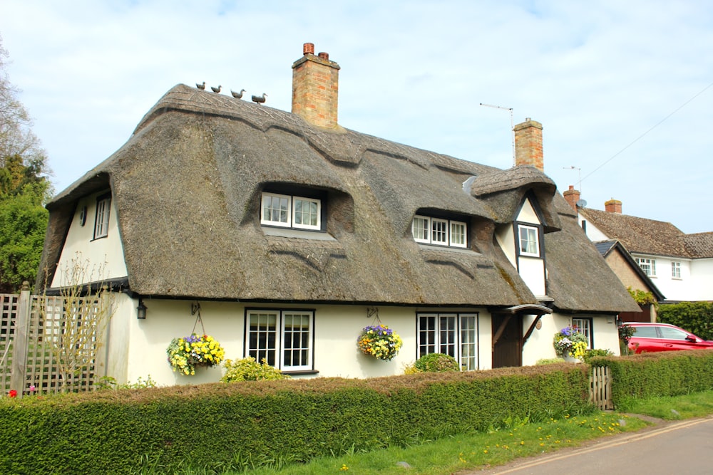a white house with a thatched roof and a car parked in front of it
