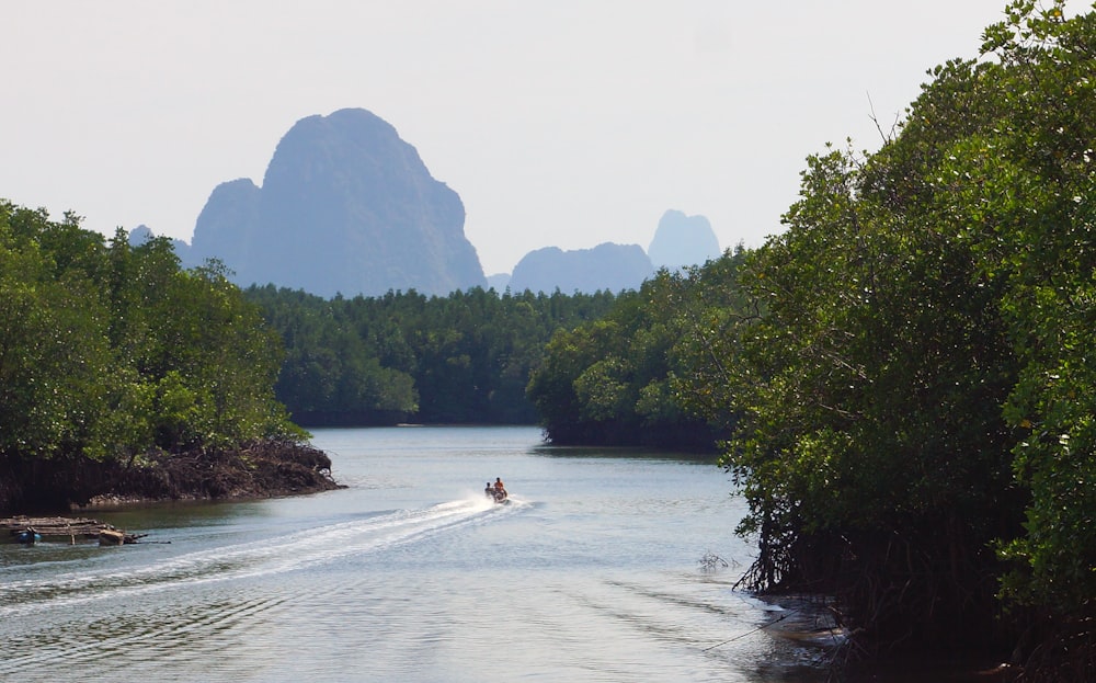 Un bateau descend une rivière avec des montagnes en arrière-plan