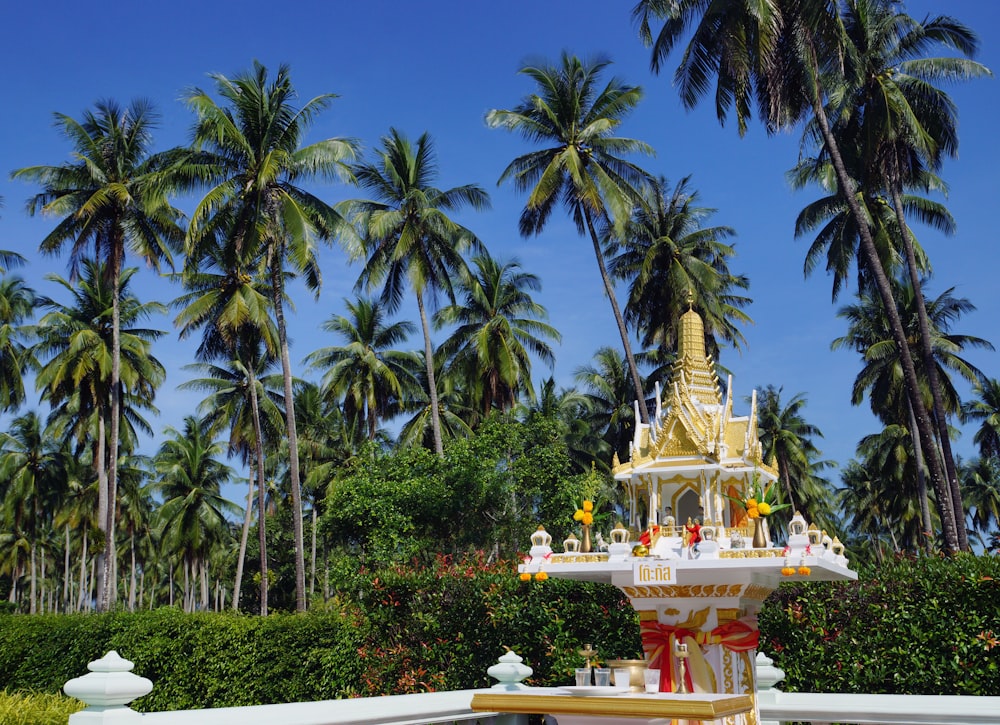 a white and gold fountain surrounded by palm trees