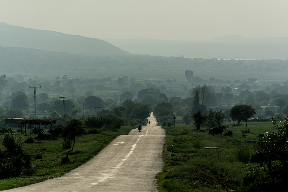 a dirt road in the middle of a lush green field