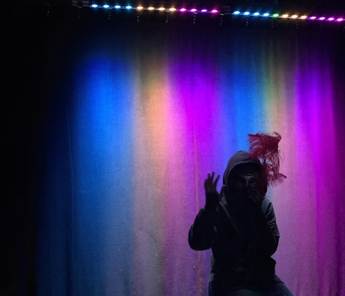 Founder performing the signature majestic walk in royal blue and silver attire against a softly lit stage backdrop.