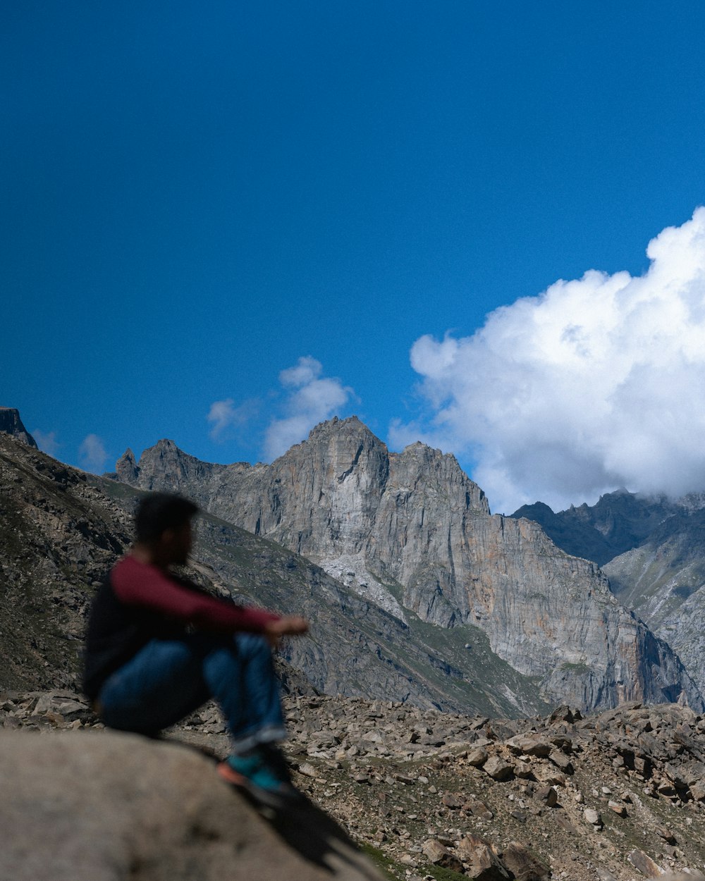 a man sitting on top of a rock next to a mountain