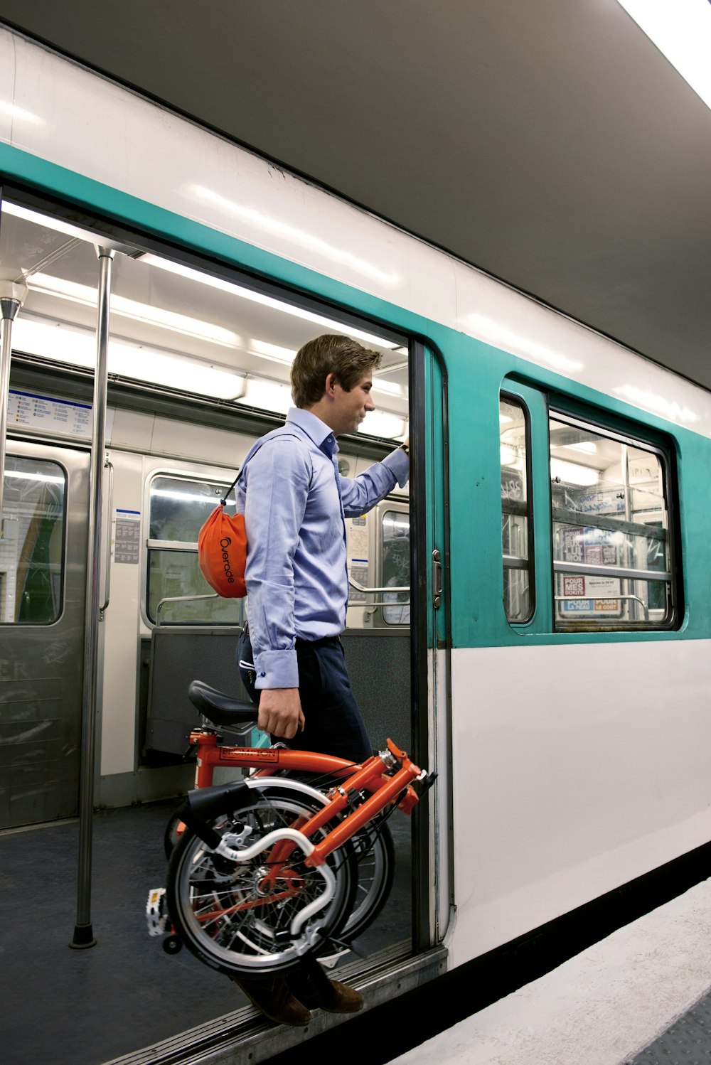 Un homme debout à côté d’un train vert et blanc