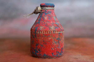 a red and blue vase sitting on top of a table