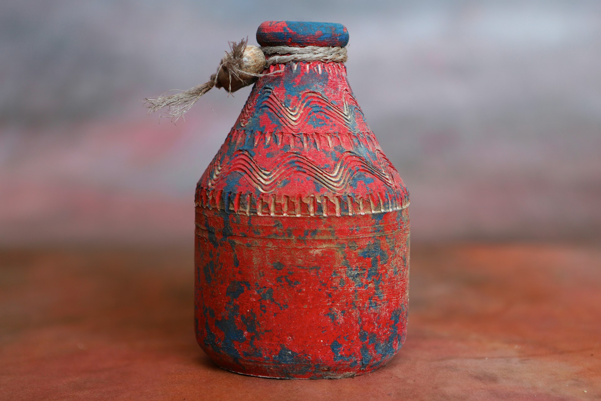 a red and blue vase sitting on top of a table