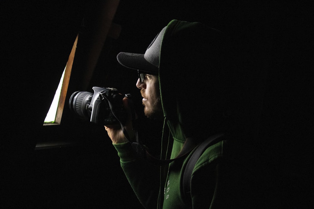 a man in a hoodie taking a picture with a camera