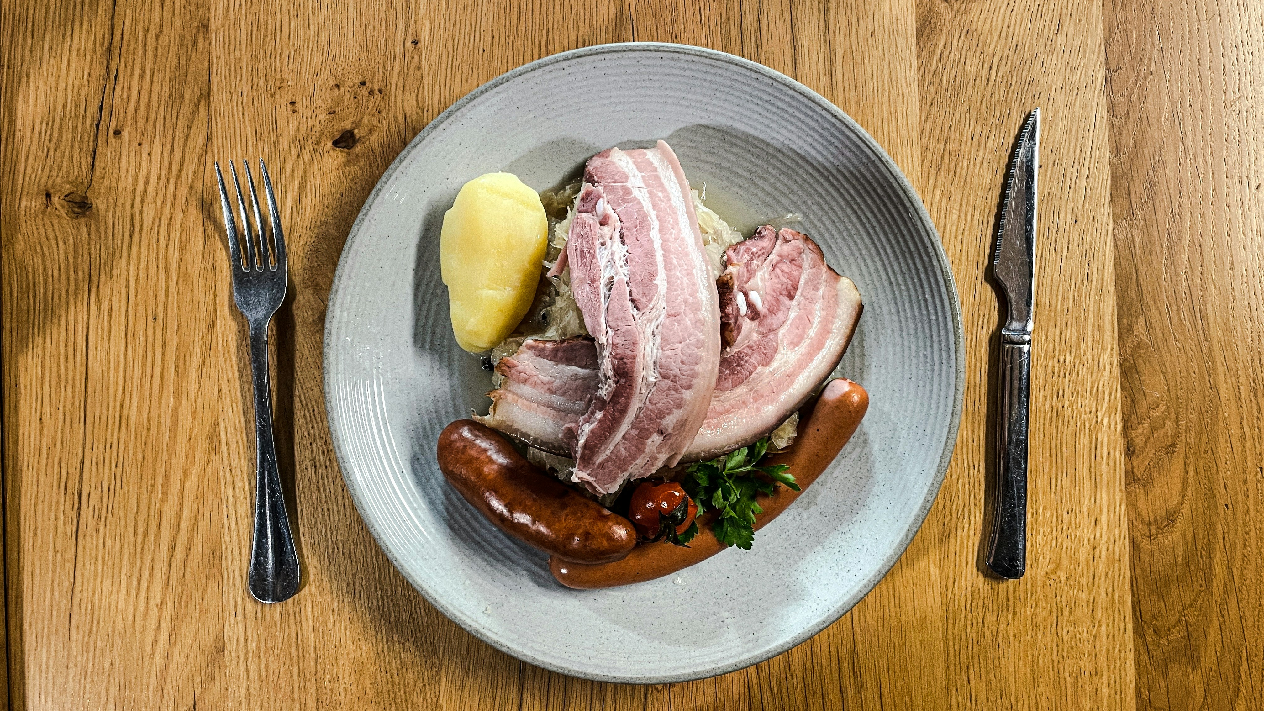 a plate of meat, potatoes, and a hot dog on a table