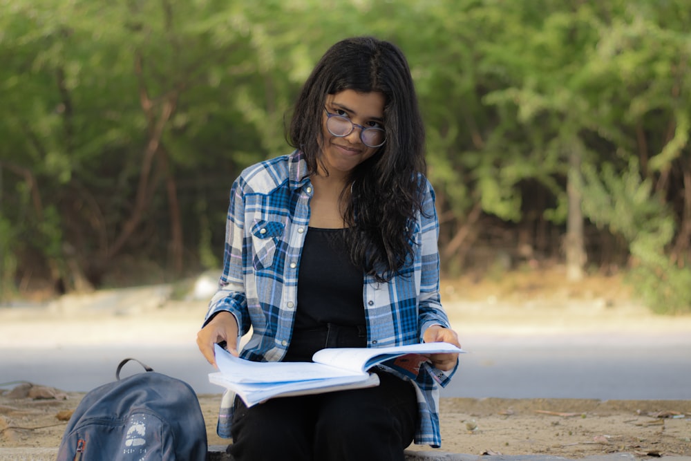 a woman sitting on the ground reading a book