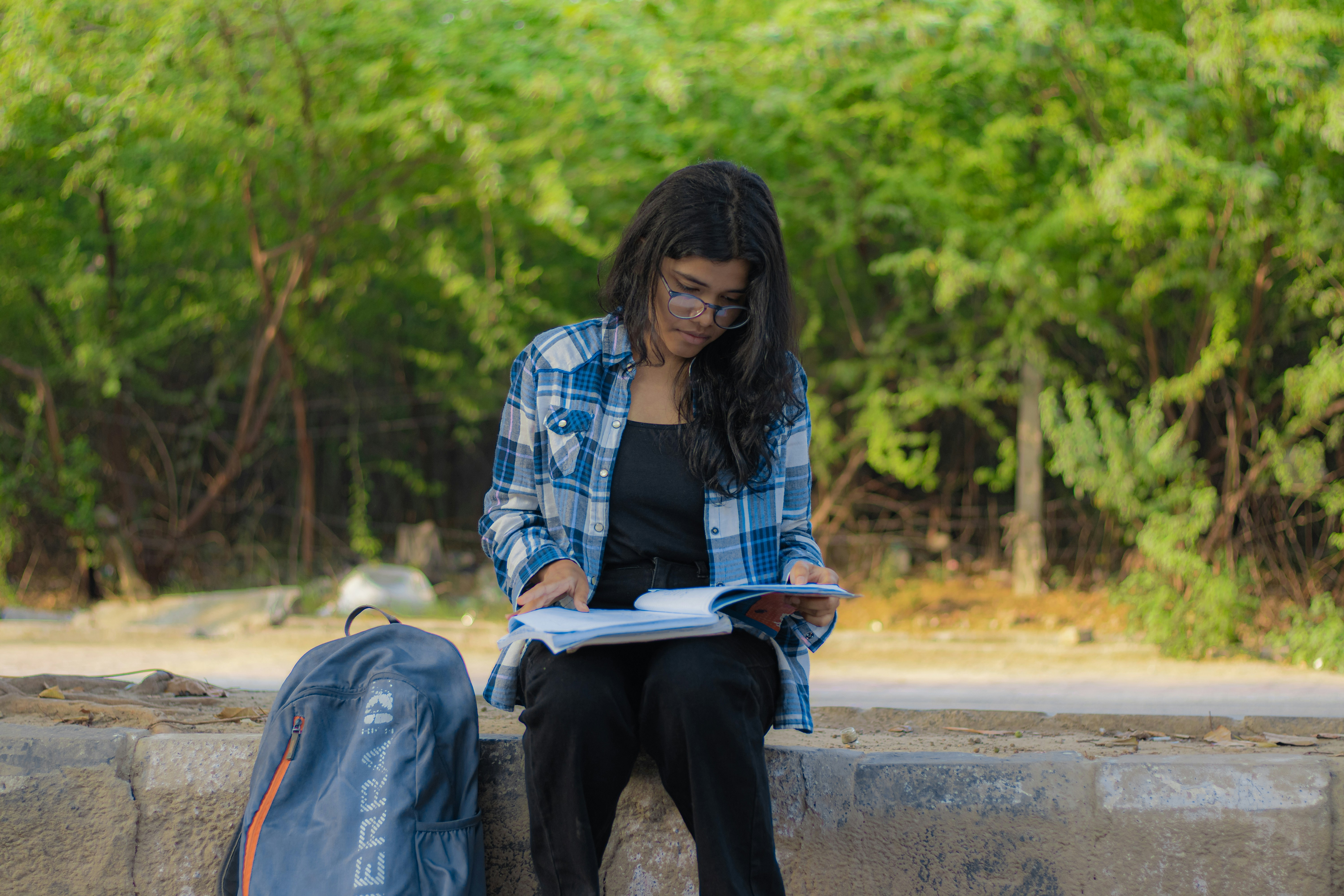 a woman sitting on a wall reading a book