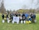 A diverse group of people smiling while holding reusable bags in a community park.