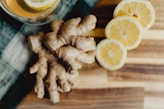 a glass of orange juice next to sliced lemons and ginger