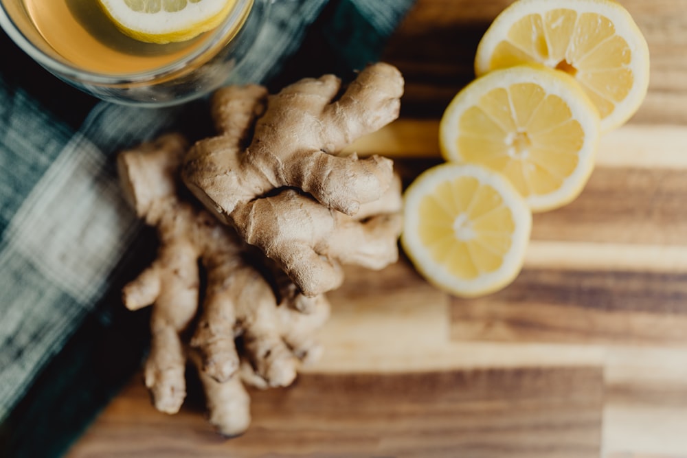 a glass of orange juice next to sliced lemons and ginger