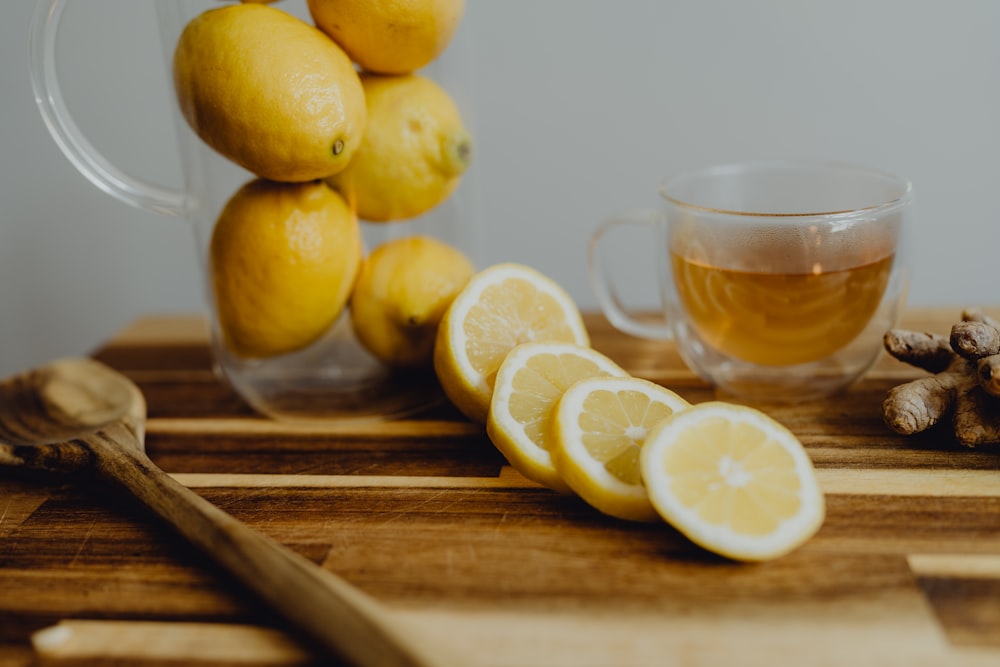 a wooden cutting board topped with sliced lemons and a cup of tea