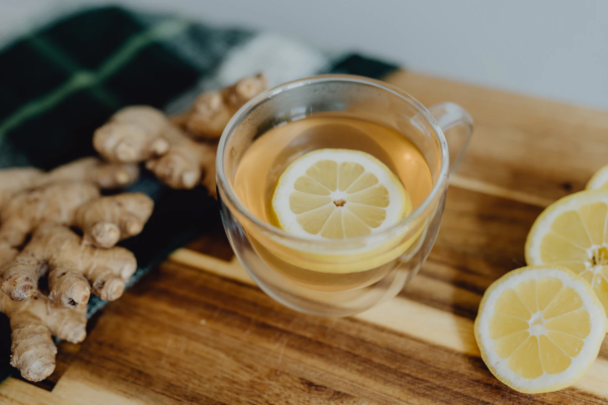 A cup of tea with lemon and ginger on a wooden cutting board
