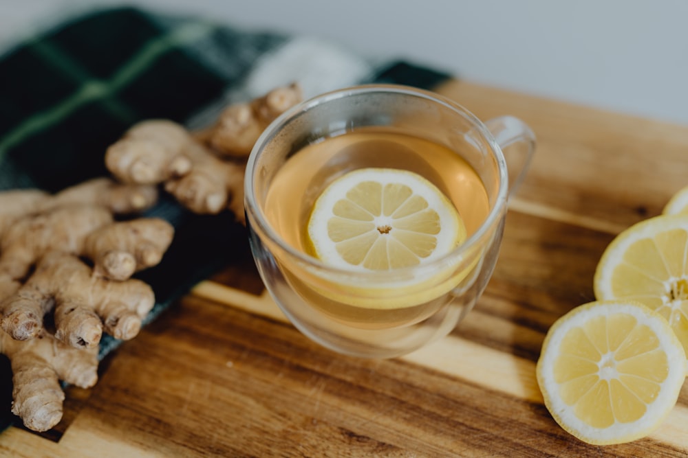 a cup of tea with lemon and ginger on a cutting board