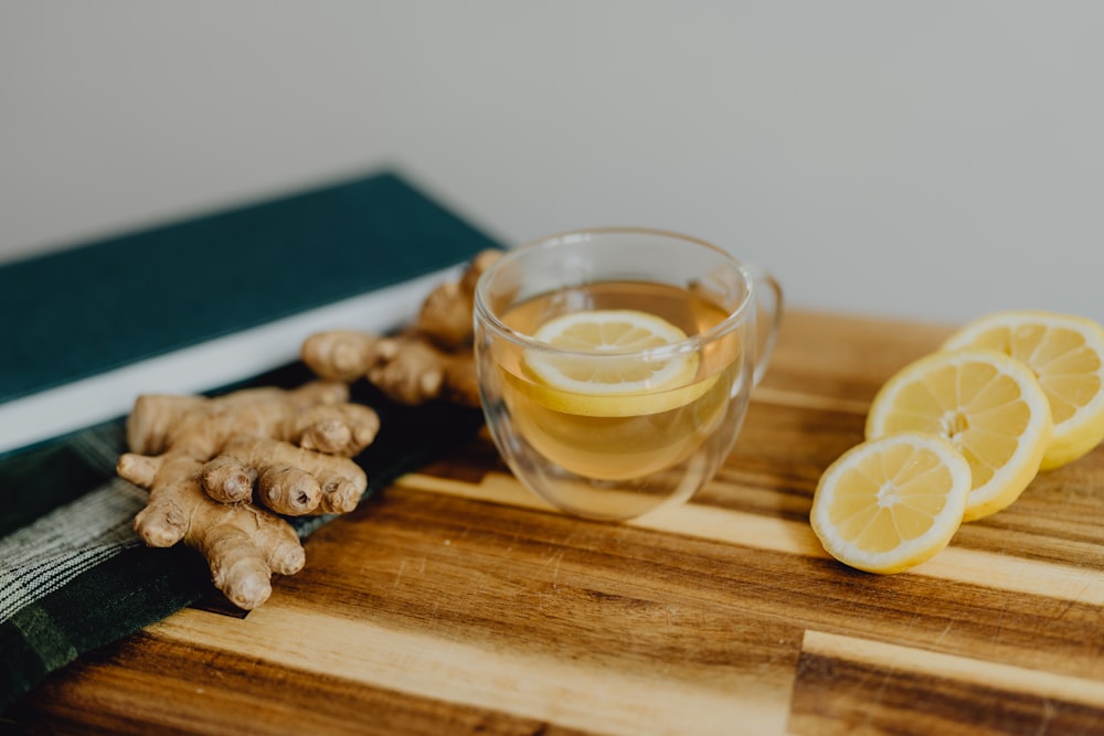 a wooden cutting board topped with sliced lemons and a cup of tea
