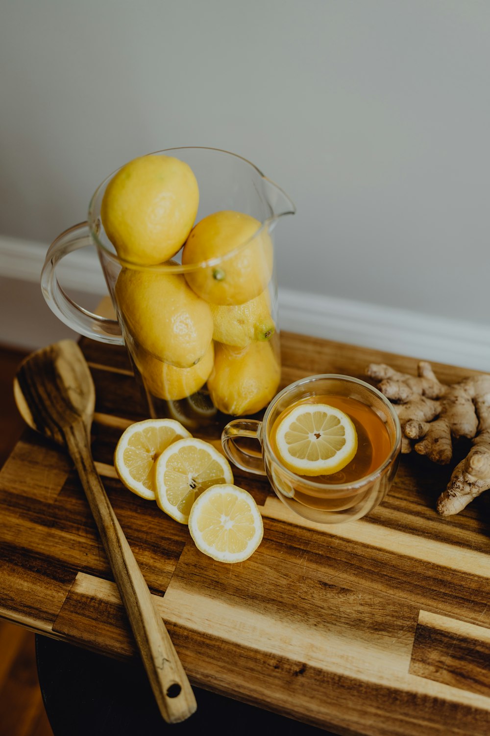 a pitcher of lemons and ginger on a cutting board