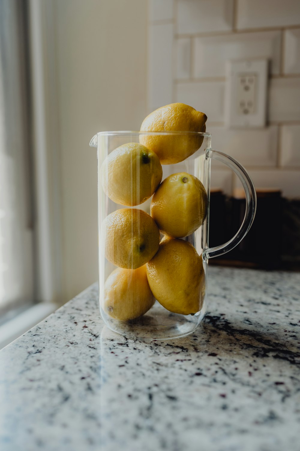 a pitcher filled with lemons on top of a counter