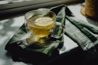 A vibrant glass of lemon tea beside a plate of assorted snacks in a cozy cafe setting.