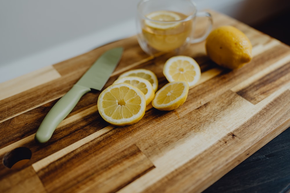 a cutting board topped with sliced lemons and a knife