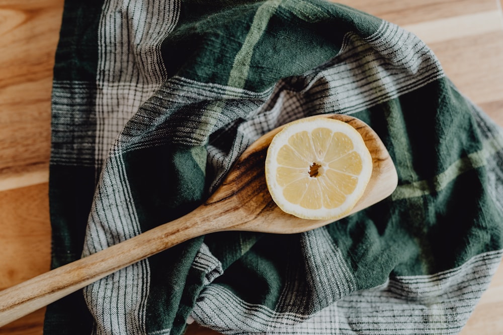 a slice of lemon sitting on top of a wooden spoon