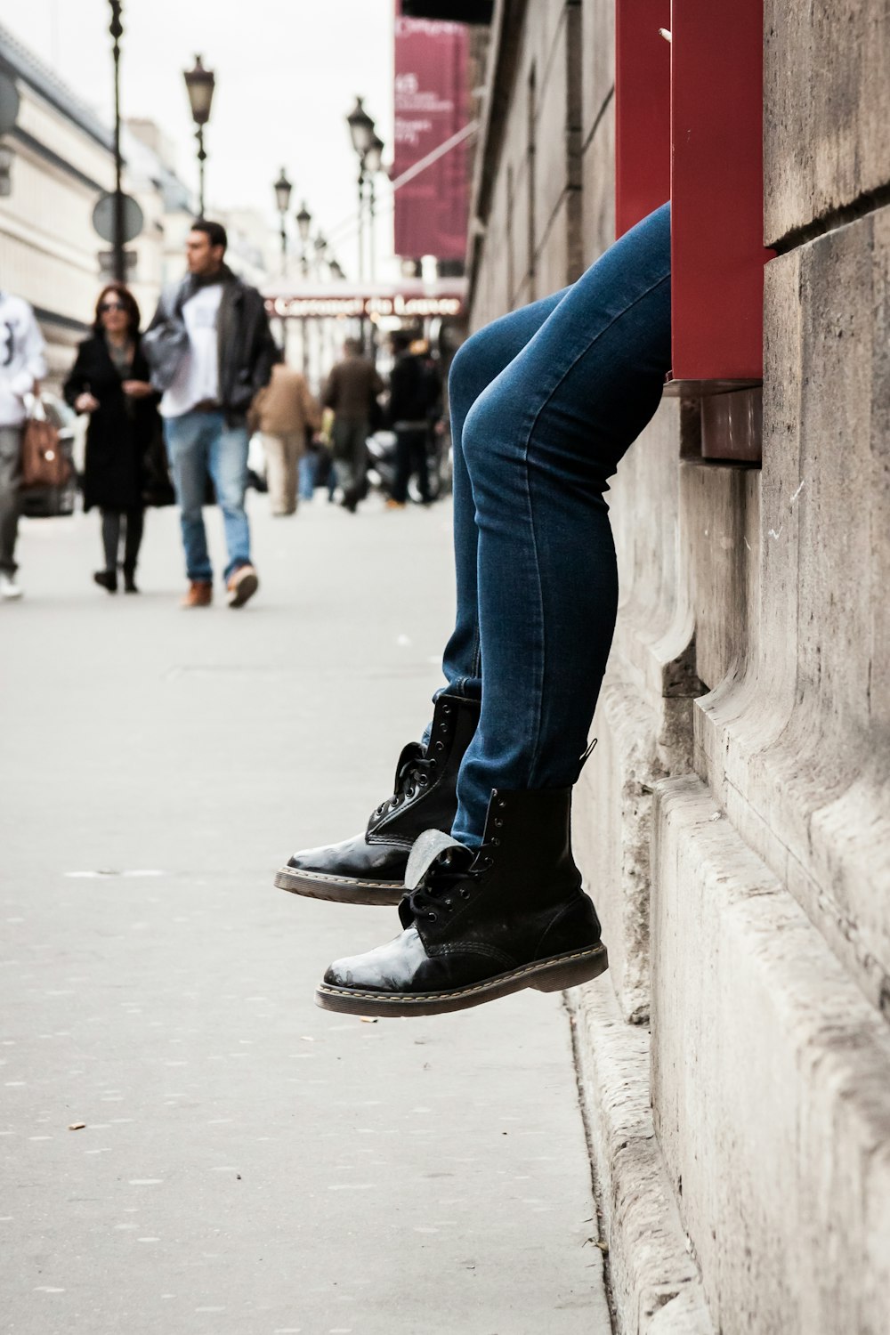 a person leaning against a wall on a sidewalk