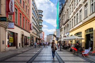 A bustling urban street scene featuring diverse people engaging with local businesses and enjoying city life.