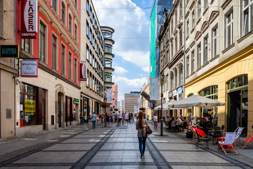 A bustling urban street scene featuring diverse people engaging with local businesses and enjoying city life.