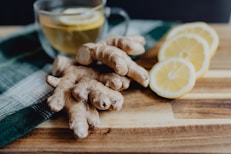a wooden cutting board topped with sliced lemons and ginger