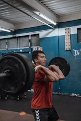Weightlifter powering through a heavy clean and jerk in a gritty gym.