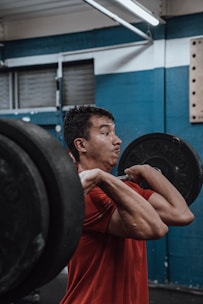 A focused man lifting heavy weights in a bright gym setting.