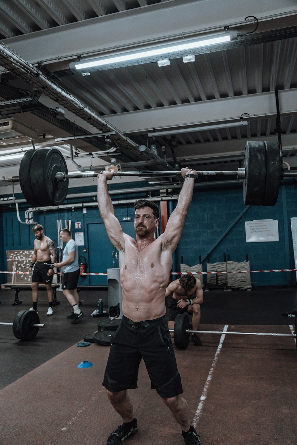 a shirtless man lifting a barbell in a gym