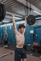 Close-up of a trainer correcting a gym member's posture during a weightlifting exercise.