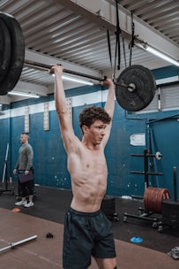 A personal trainer assisting a client with weightlifting in a modern gym setting.