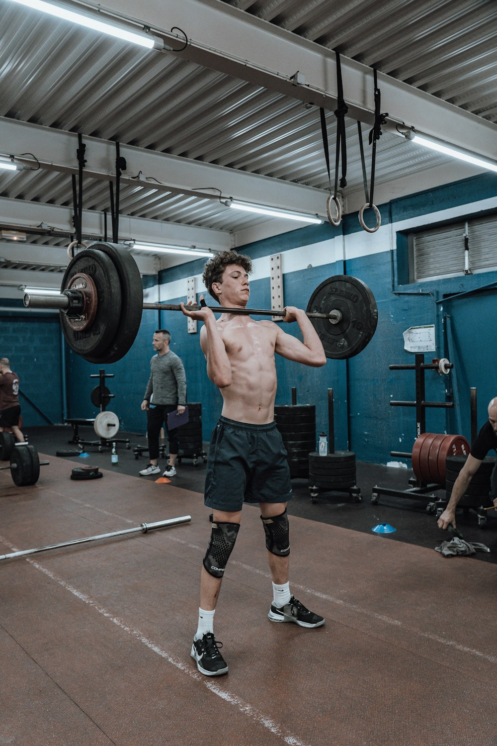 a shirtless man holding a barbell in a gym