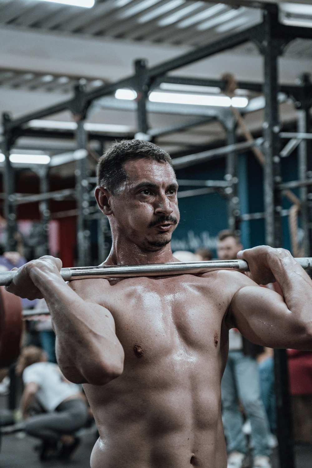 a shirtless man holding a barbell in a gym