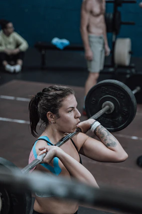 A focused young woman lifting weights at home, following an online fitness class on her laptop.