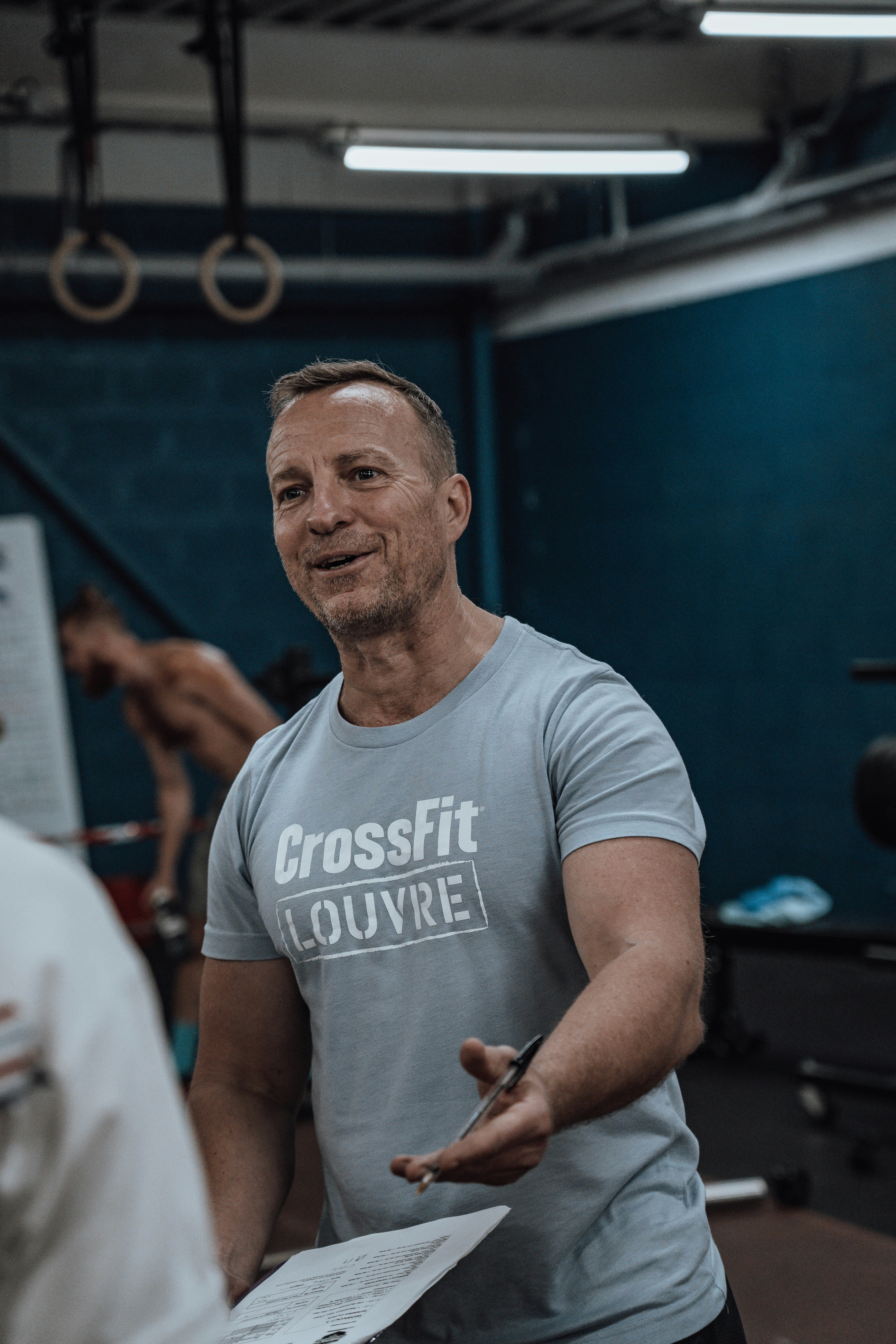 Usmievavý muž hovorí o dokumentoch o fitness v posilňovni.