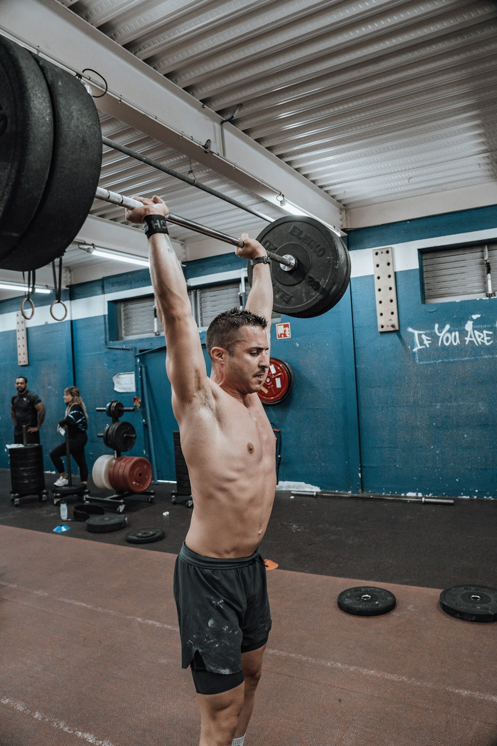 a shirtless man lifting a barbell in a gym