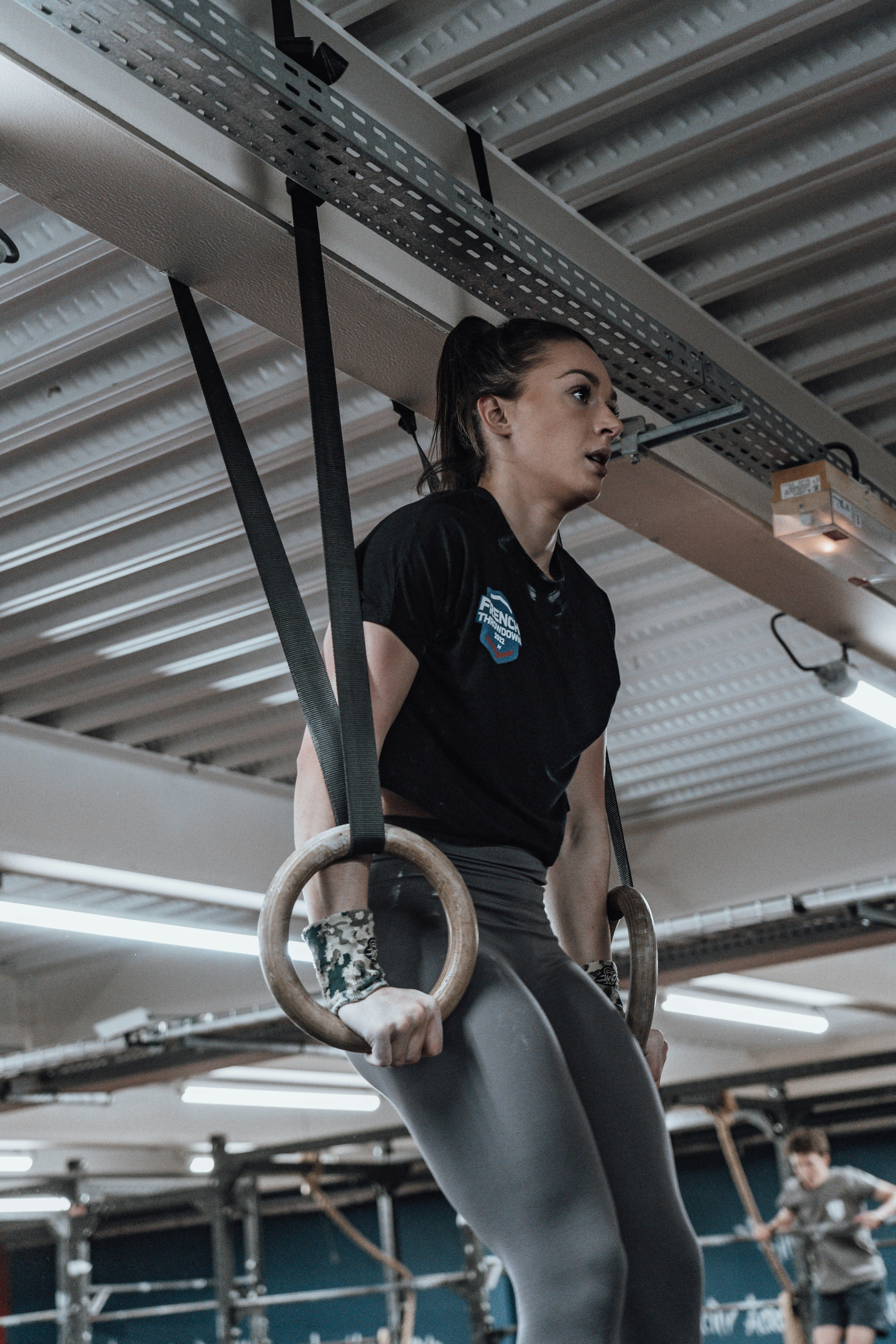 Frau in Sportkleidung macht Übungen an Ringen.