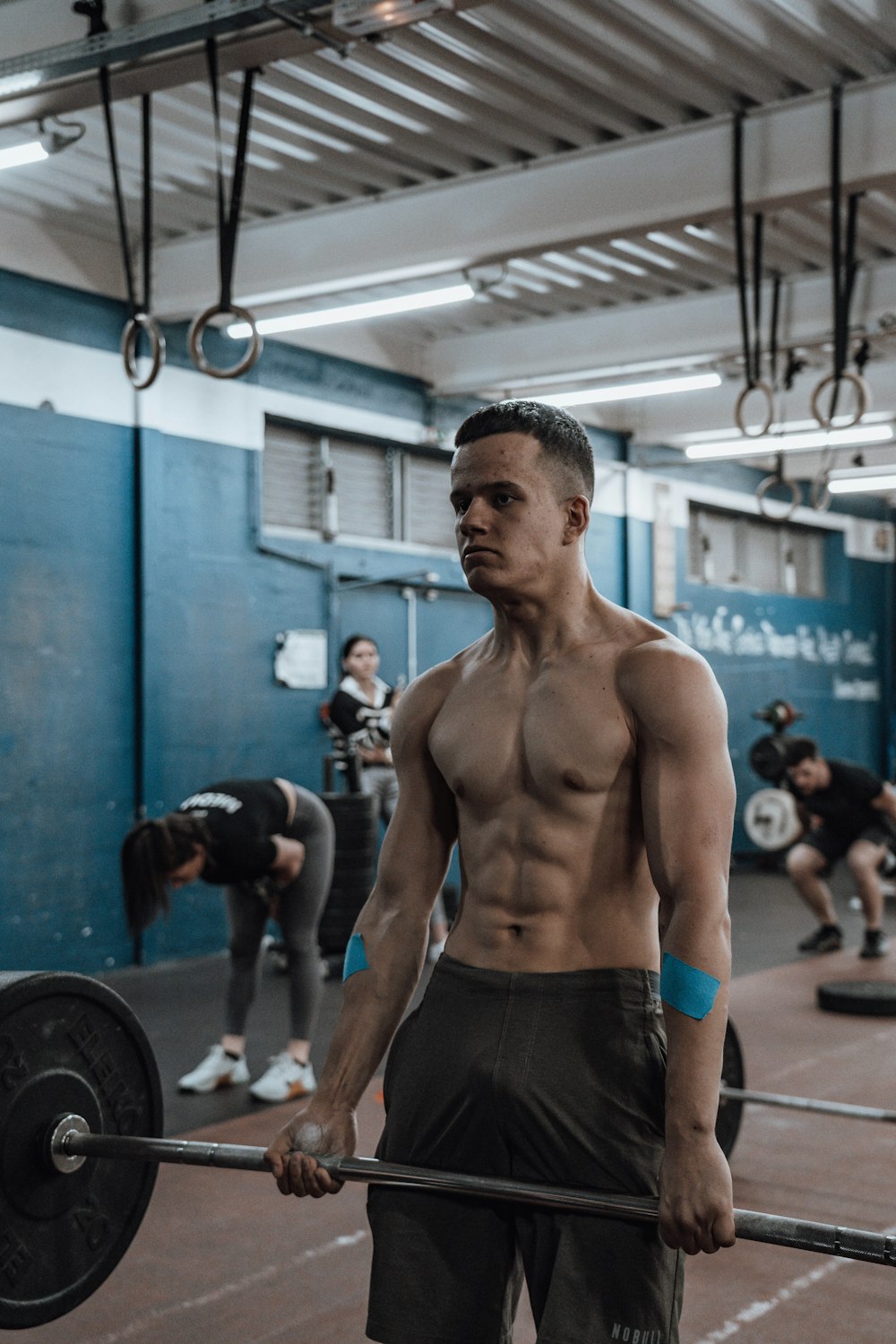 a shirtless man holding a barbell in a gym