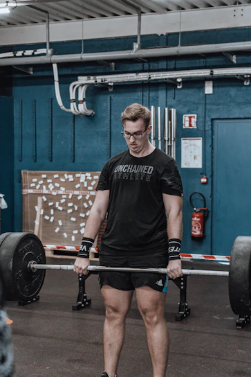 Athlete lifting weights with intense focus in a modern gym setting.